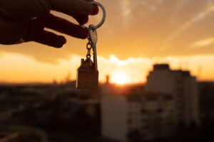 Real estate agent holding keys with a sunset background.