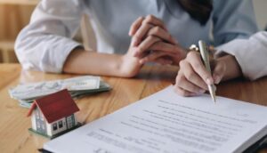 Photo features two individuals' hands as they sign a tenancy contract